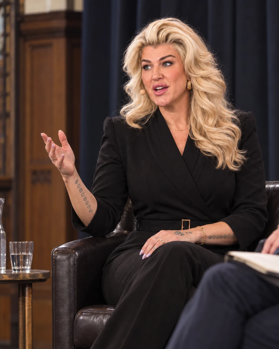 Penny Dee seated on a panel, speaking in a black outfit