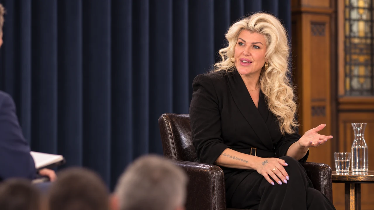 Penny Dee speaking on a panel with an open hand gesture